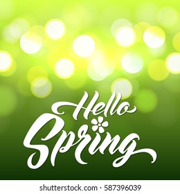HELLO SPRING Hand lettered style spring background. Handmade vector calligraphy on abstract glowing green background with bokeh light