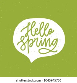 Hello Spring phrase handwritten with elegant cursive font or script inside speech balloon or bubble on green background. Springtime seasonal lettering or inscription. Hand drawn vector illustration.
