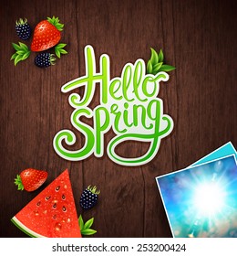 Hello Spring vector card design with fresh berries, watermelon and instant photos of a bright sunburst in a blue sky with a central flowing green greeting for the new season over textured wood