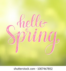 Hello Spring. Vector greeting card with hand written calligraphic phrase on a blurred background.