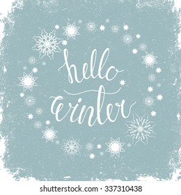 Hello winter, inspirational quote. Ink hand lettering on blue textured background. Snowflake Wreath Typographical Backdrop. Postcard, poster, textile & t-shirt design. Vector illustration.