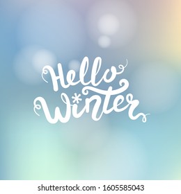 Hello winter title. Brush lettering at blurred winter background with bokeh lights. Vector card design with handwritten calligraphy