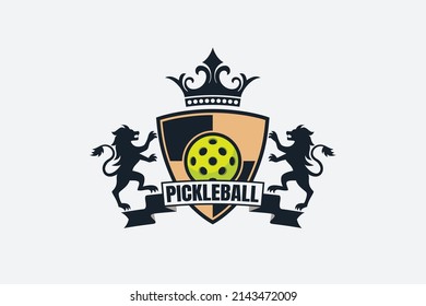 heraldic pickleball logo with a ball, ribbon, shield, lions, and crown.