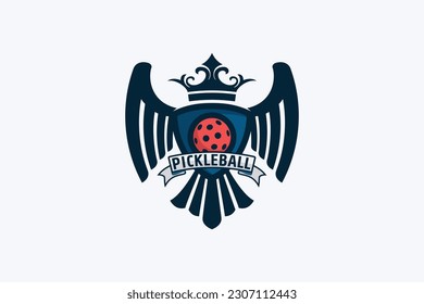 heraldic pickleball logo with a combination of a ball, eagle wings and tail, ribbon, and crown in heraldic style.