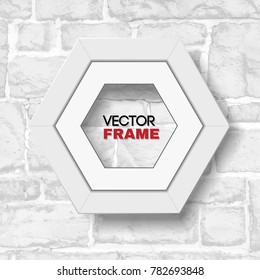 Hexagonal white picture frame hanging on white brick wall