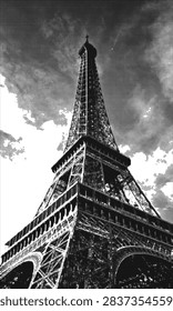 High-contrast black and white photo of the Eiffel Tower taken from a dramatic low angle, highlighting the iron lattice structure against a cloudy sky and a bold halftone graphic effect.