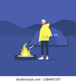 hiking in forest, young male tourist roasting marshmallows on a campfire, 