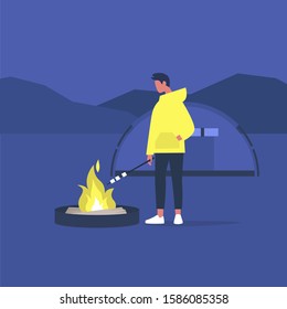 hiking in forest, young male tourist roasting marshmallows on a campfire, 