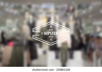 Hipster insignia in boutique display window with fashion dummy models, blurred background. 