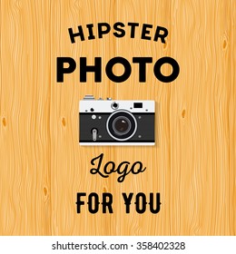 Hipster logotype with old camera for studio or photographer on wooden background.