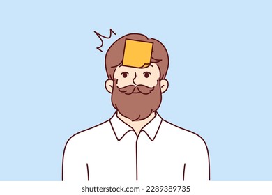 Hipster man with sticky notes on forehead looking at camera smiling. Hipster guy with mustache and beard tries to guess what is written on sticker playing with colleagues or friends 