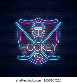 Hockey championship neon sign with hockey sticks, puck and goalkeeper helmet in shield frame. Ice hockey competition logo, emblem, symbol design. Vector illustration.