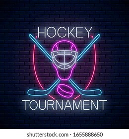 Hockey tournament neon sign with hockey sticks and puck and goalkeeper mask on dark brick wall background. Ice hockey competition logo, emblem, symbol design. Vector illustration.