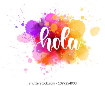 Hola - Hello in Spanish. Handwritten modern calligraphy inspirational text on multicolored watercolor paint splash.