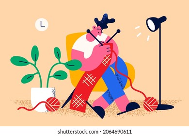 Home leisure hobbies and knitting concept. Young smiling man cartoon character sitting at home in armchair knitting scarf of red wool vector illustration 