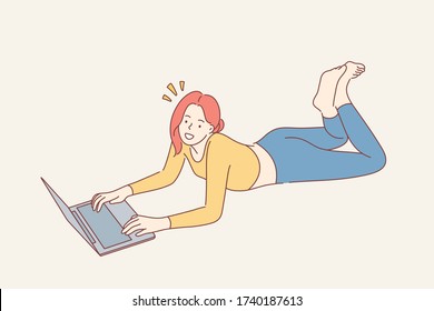 Home rest, leisure time concept. Young happy smiling woman girl teenager freelancer cartoon character lying on floor with laptop and looking straight at camera. Recreation and relaxation lifestyle.