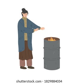 Homeless dirty woman standing and warming up near burning trash can