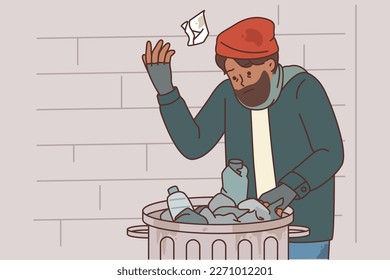 Homeless man digs through garbage to find food due to poverty and social inequality caused by unemployment. Beggar homeless guy near trash can for concept of urban problems and poverty after crisis