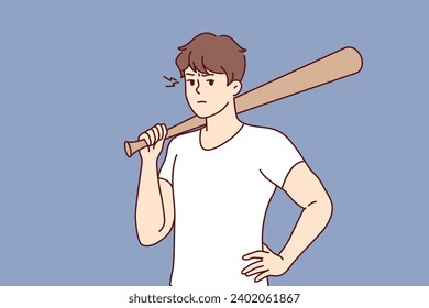Hooligan guy with baseball bat in hand stands with hand on belt and threatens to beat up passerby. Male hooligan or gangster uses stick to intimidate people and extort or rob store