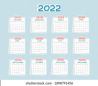 Horizontal Calendar for 2022 from January to December. Every month is on squared paper with dots, piece of newspaper is at the bottom, pink scotch, color patterned adhesive tape is on the top
