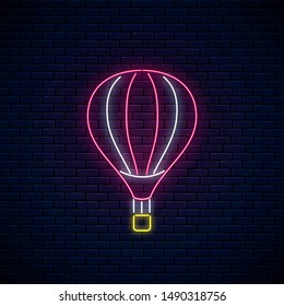 Hot air balloon glowing neon icon on dark brick wall background. Flying hot air ballon in neon style. Vector illustration.