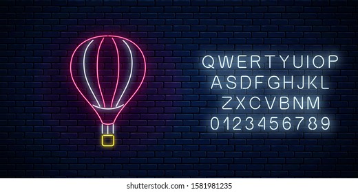 Hot air balloon glowing neon icon on dark brick wall background with alphabet. Flying hot air ballon in neon style. Vector illustration.