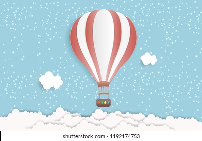 Hot air balloon in the sky with clouds and snowing. Origami paper art and digital craft style. Vector illustration