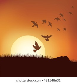 The hot glowing sun sets behind a hill silhouetting the field grass
