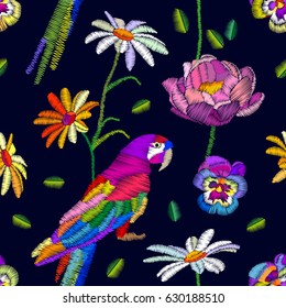 Hot tropical summer. Seamless vector pattern with parrot and flowers. Stylized embroidered texture.
