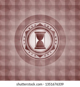 hourglass icon inside red seamless emblem or badge with abstract geometric pattern background.