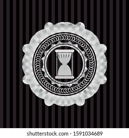 hourglass icon inside silvery badge or emblem