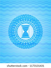 hourglass icon inside sky blue water style emblem.