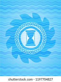 hourglass icon inside water wave representation emblem.