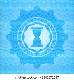 hourglass icon inside water wave representation badge background.