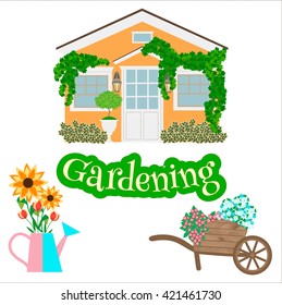 House, garden wheelbarrow, watering can and garden plants. 