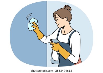 Housewife woman cleaning apartment, wiping wall or glass using antibacterial spray, dressed in apron and gloves. Happy girl works as maid in motel and cleaning preparing room for arrival of guests