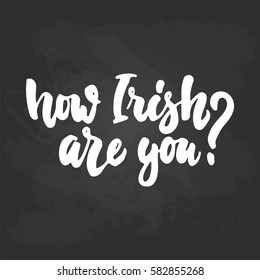 How Irish are you - hand drawn lettering phrase for holiday Saint Patrick's day isolated on the black chalkboard background. Fun brush ink inscription for photo overlays, greeting card, poster design