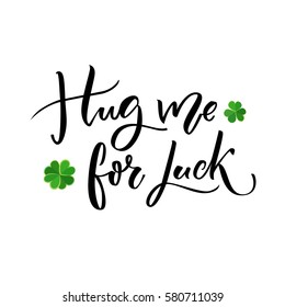 Hug me for luck. Funny St. Patrick's day saying for t-shirts and cards. Brush lettering design with clovers.