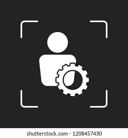 human with gear icon. White object in camera autofocus on dark background