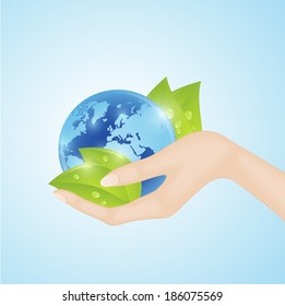 Human hand holding blue world globe with green leaves 