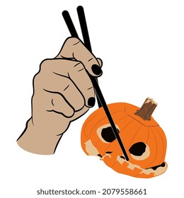 Human hand holding Jack-o'-lantern carved pumpkin with chopsticks. Creative funny Halloween design.