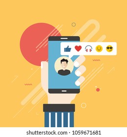 Human hand holding mobile phone with social network feedback emoticons : thumbs up, like, smile, earphone, face sunglasses on screen. Concept of facial expression, text messaging and using phone.