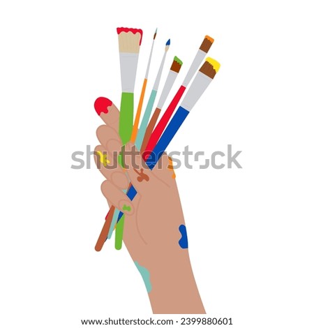 Human hand holding paint brushes.