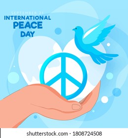 Human Hand Holding Peace Symbol with Pigeon and Heart Shape Earth Globe on Blue Background for 21st September, International Peace Day.