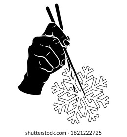 Human hand holding snowflake with two chopsticks. Creative winter concept. Black and white silhouette.