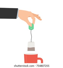 human hand holding tea bag and cup on white background