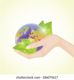 Human hand holding world globe with green leaves 