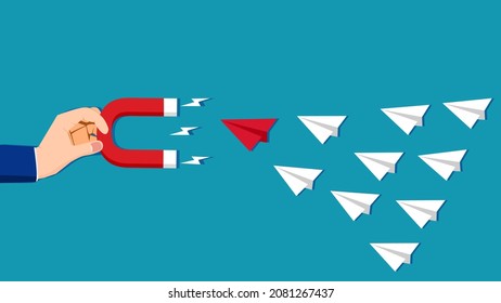 A human hand that attracts a paper plane with a magnet. The idea of attracting leaders