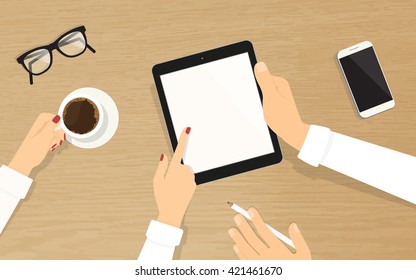 Human hands hold a blank tablet pc with empty display and showing something to his colleague. Top view of realistic wooden table on the office with grasses, smartphone and coffee cup