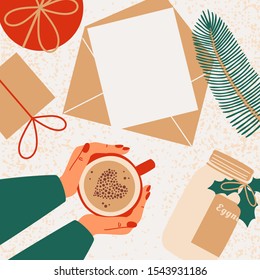 Human hands hold mug with coffee. Christmas gifts, fir branch, bottle with eggnog are scattered around the greeting card with copy space for text. 